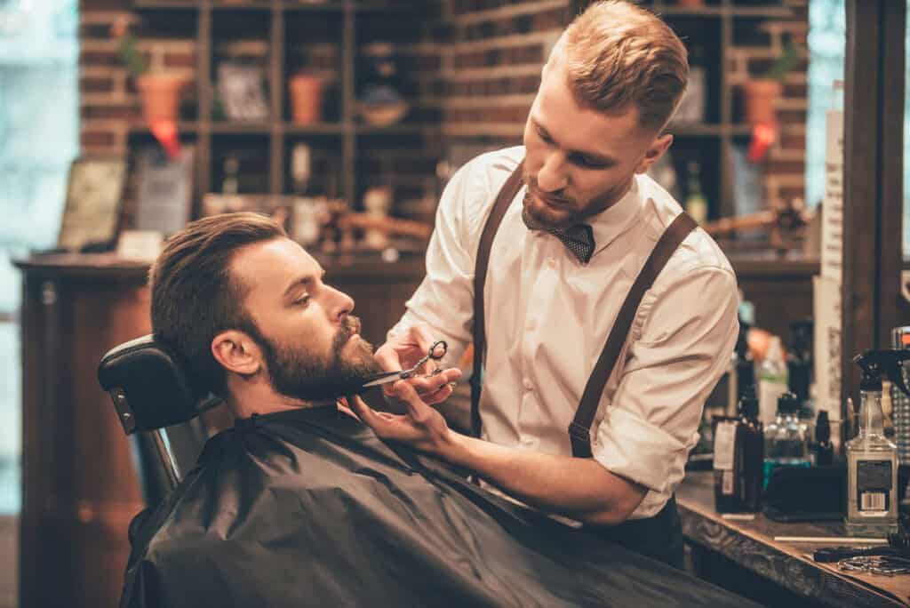 A barber shop with a man getting a beard grooming