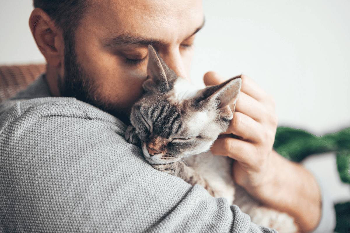 a man hugging and cuddling a tabby cat