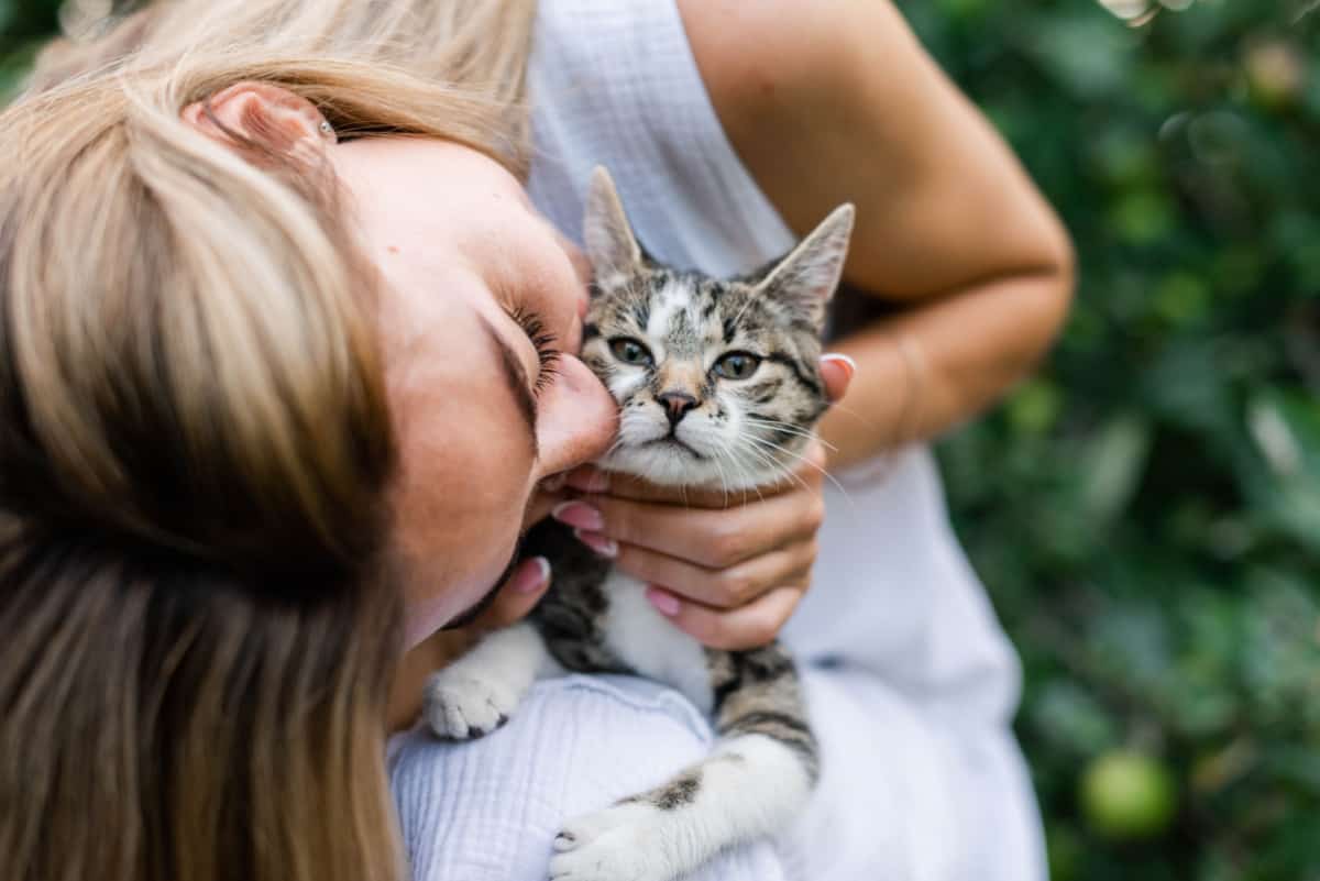 woman kisses a cat in the garden