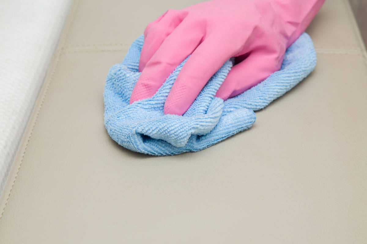 a hand with pink glove wiping surface with damp towel or cloth